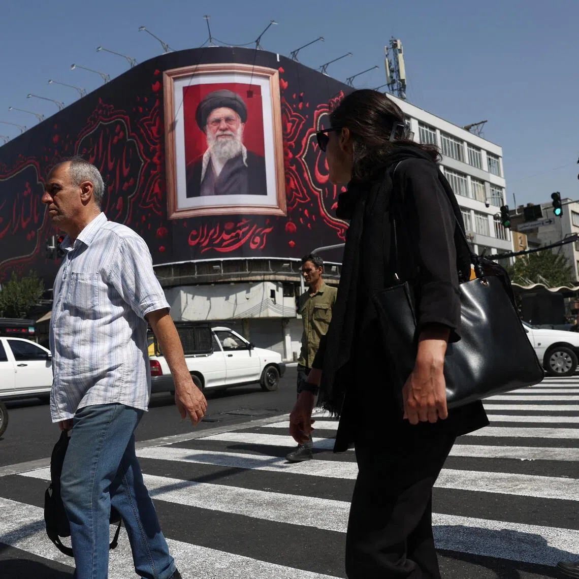 Iranians walk past a billboard with an image of Iran’s late supreme leader Ayatollah Ali Khamenei in Tehran.