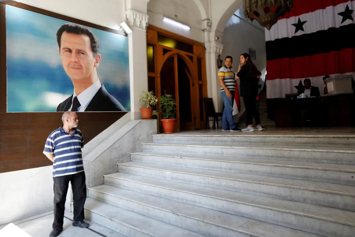 A man stands in front of a poster depicting Syria's President Bashar al-Assad at a polling station, during parliamentary elections in Damascus, Syria July 15, 2024. REUTERS/Yamam al Shaar