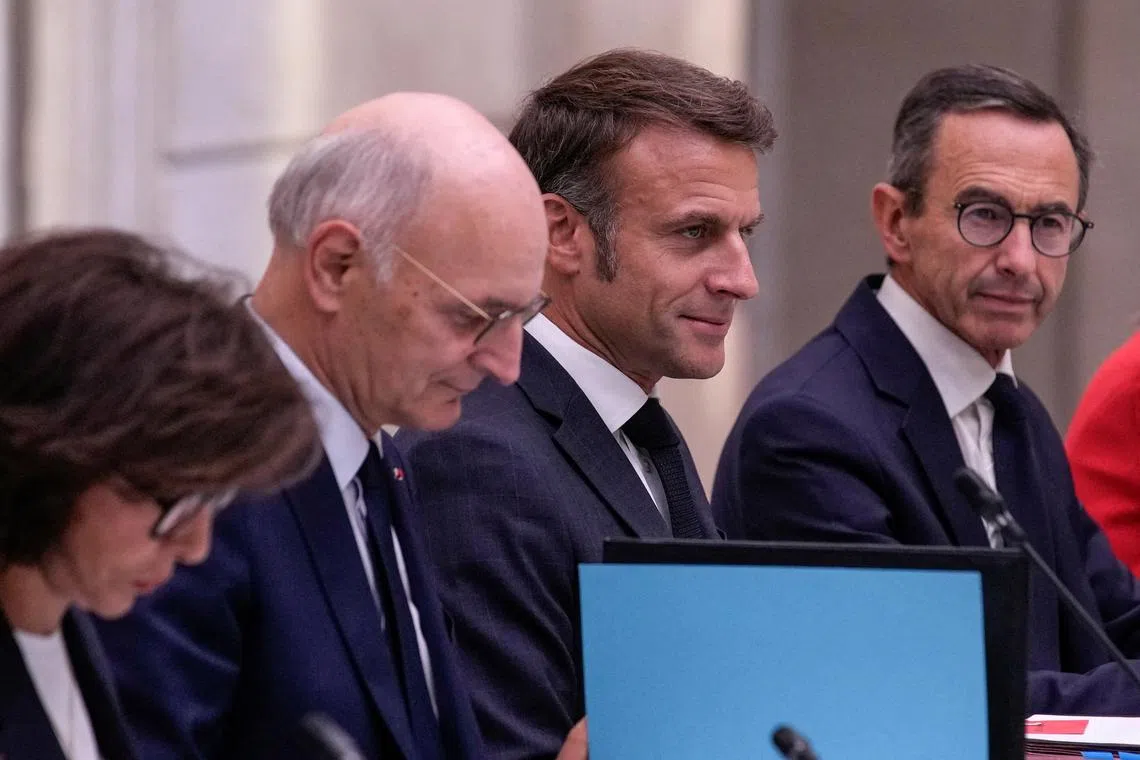 French President Emmanuel Macron is flanked by new Justice Minister Didier Migaud and new Interior Minister Bruno Retailleau during the first weekly cabinet meeting at the Elysee Palace Monday, Sept. 23, 2024 in Paris, France.     Christophe Ena/Pool via REUTERS