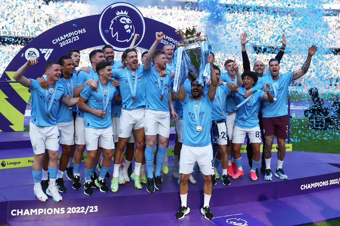 Manchester City's Ilkay Gundogan lifts the trophy as he celebrates with teammates after winning the Premier League on Sunday.