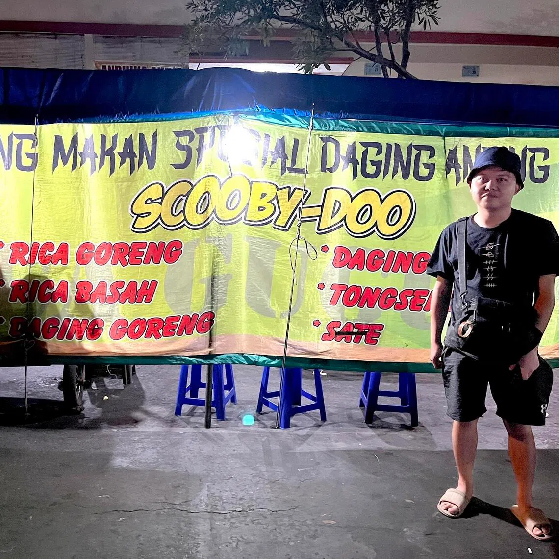 wydog - A tourist poses in front of "Rumah Makan Spesial Daging Anjing", which translates to Food Stall specialising in Dog Meat, in Solo, Central Java province. 

Photo credit J. Radian