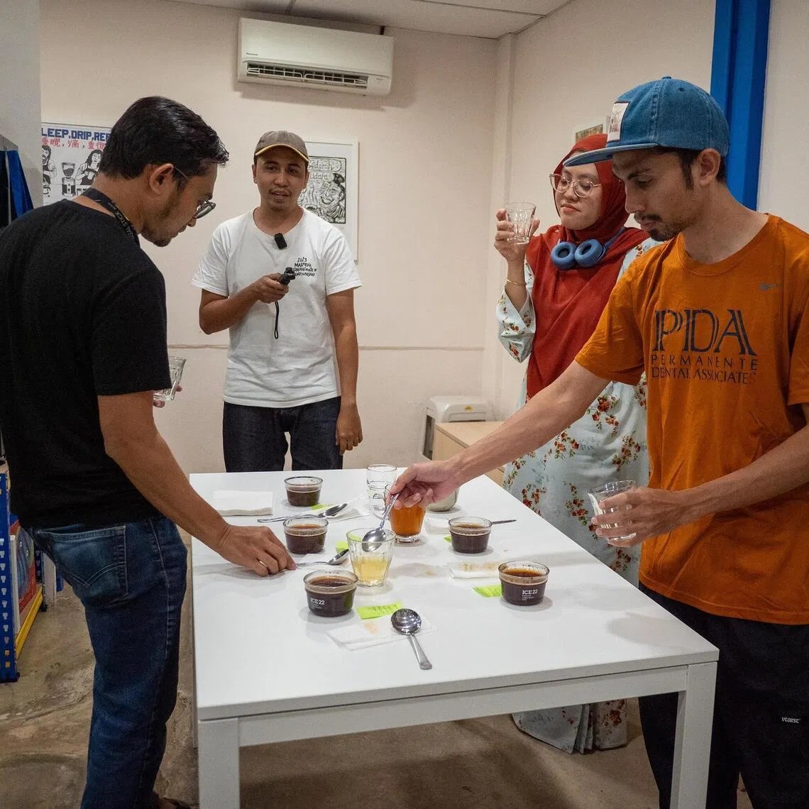 hakopi - Cafe owner Akmal Zamri, second from left, recording a coffee cupping session at Temerloh's Kopi Empat Petang with friends.
ST PHOTO: HADI AZMI