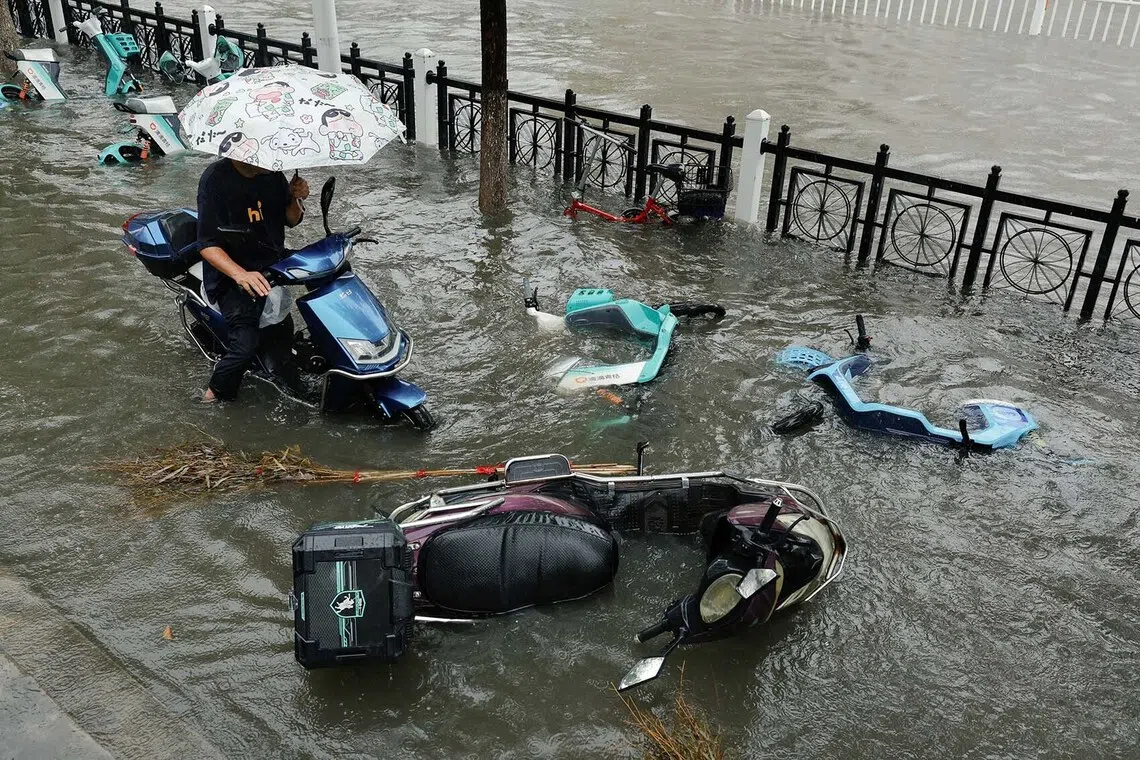 A person rides an electric scooter on a flooded street while avoiding fallen bicycles during heavy rain brought by Typhoon Dolphin after it weakened into a tropical storm, in Xiangyang, Hubei province, China, August 11, 2026. REUTERS/Go Nakamura TPX IMAGES OF THE DAY