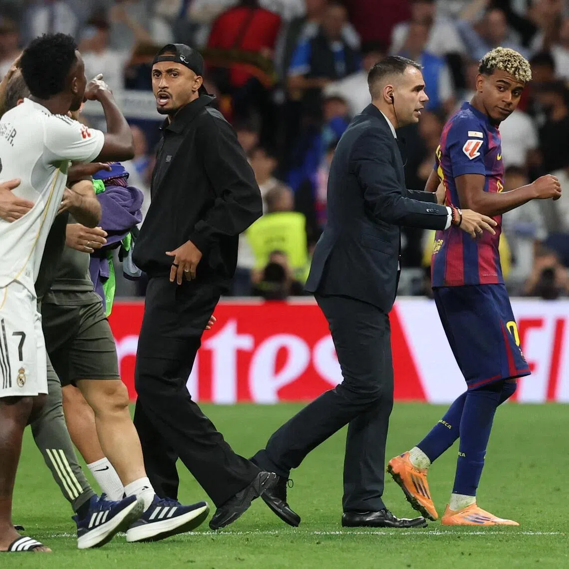 Real Madrid's Vinicius Junior argues with Barcelona's Lamine Yamal at the end of the match.