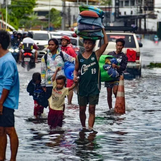 Residents carrying their belongings, wade through a flooded street in Mandaue City, Cebu province on Nov 4.