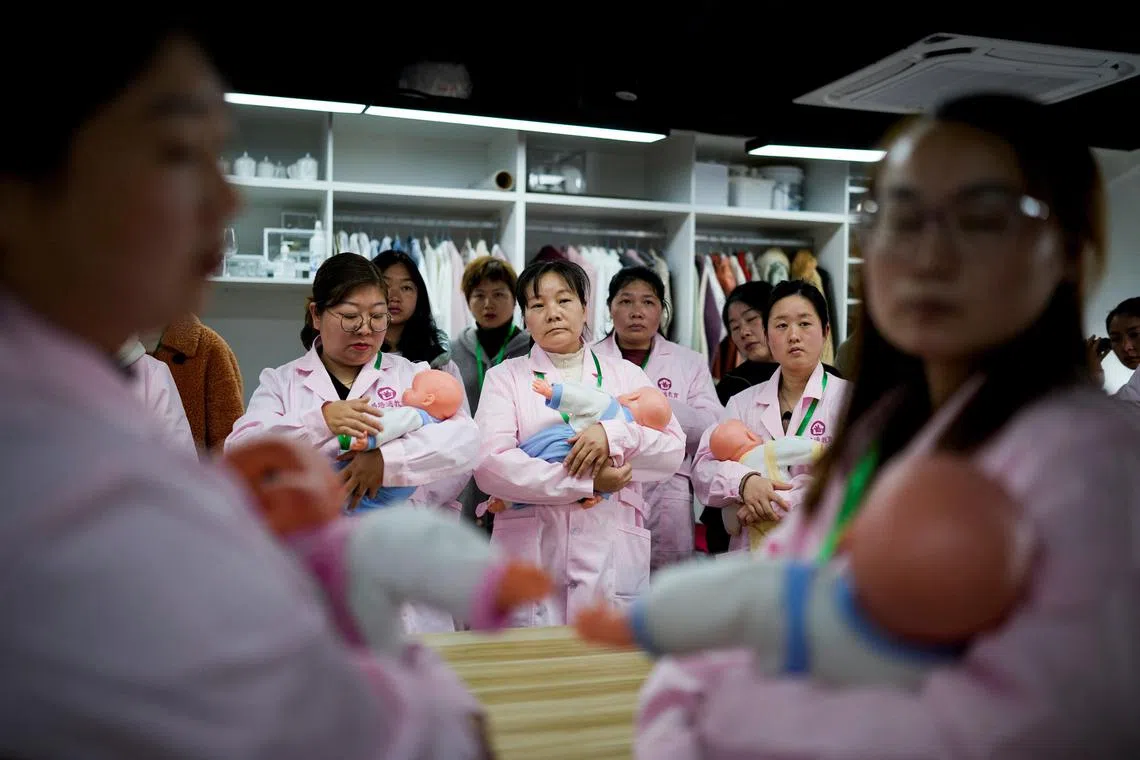 Women train with plastic baby dolls as they take part in a nursing skills class for confinement carers, at Yipeitong training centre in Shanghai, China March 2, 2023. REUTERS/Aly Song