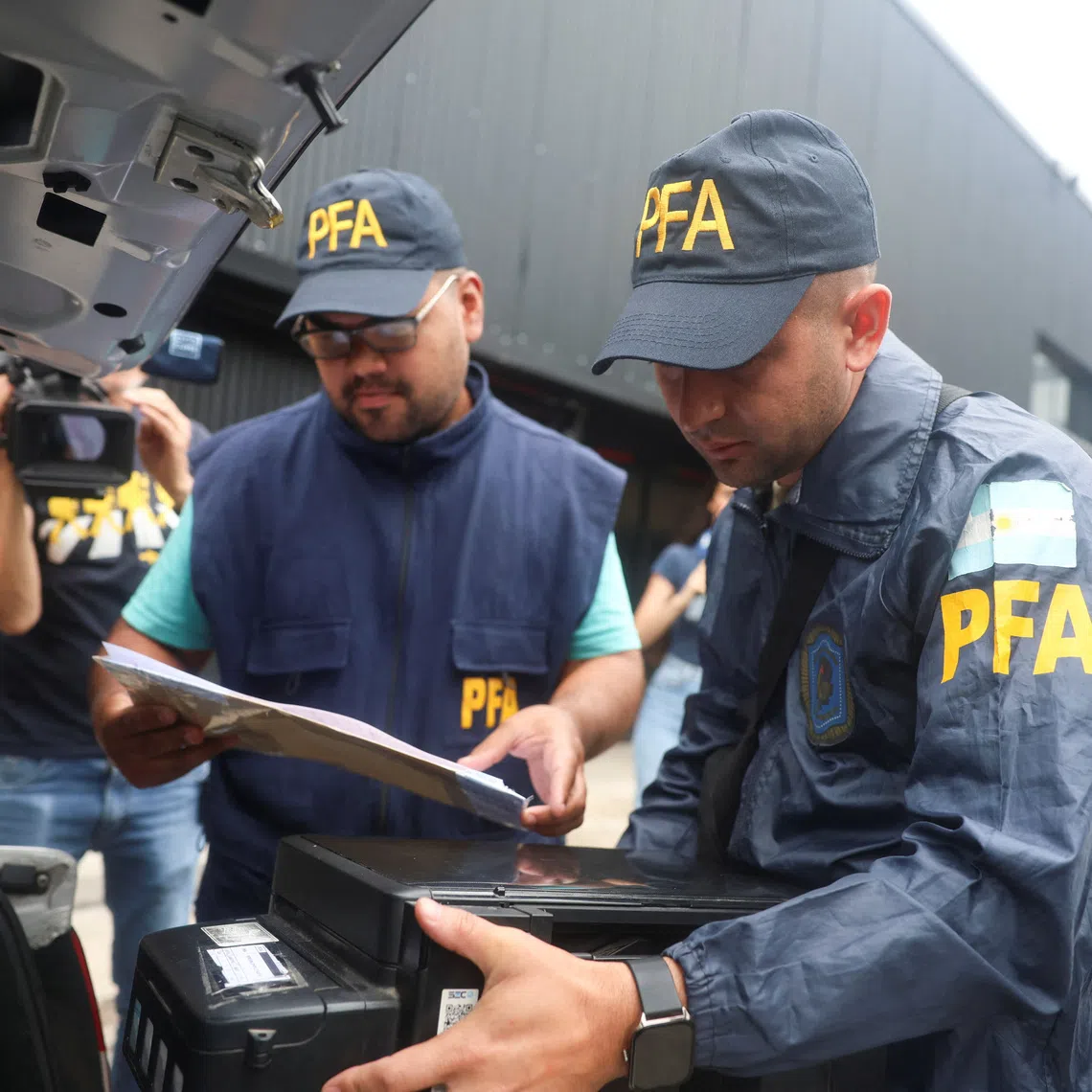 A member of the Argentine Federal Police places a printer inside the trunk of a car after seizing it from Claudio Chiqui Tapia stadium, which belongs to the soccer team Barracas Central, where Federal Police raid amid investigation into alleged money laundering, according to local media, in Buenos Aires, Argentina, December 9, 2025. REUTERS/Cristina Sille