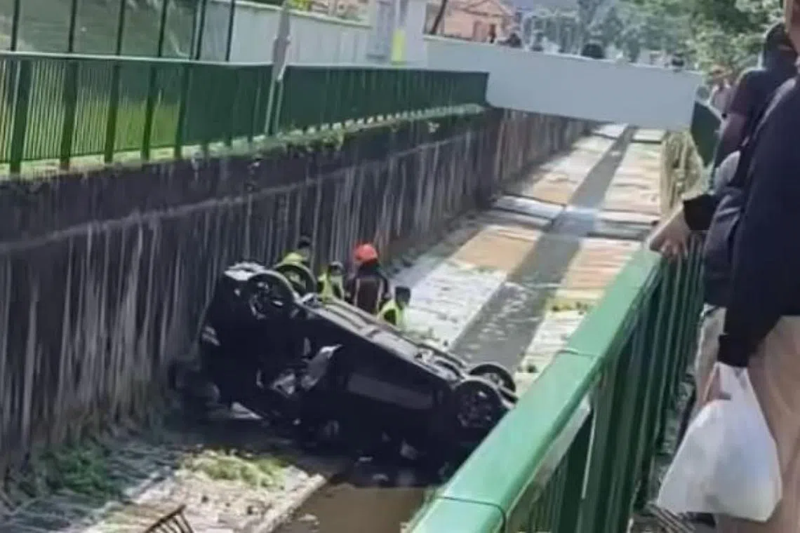 Video on social media showed the black car flipped upside down in a canal while several individuals tended to the driver.