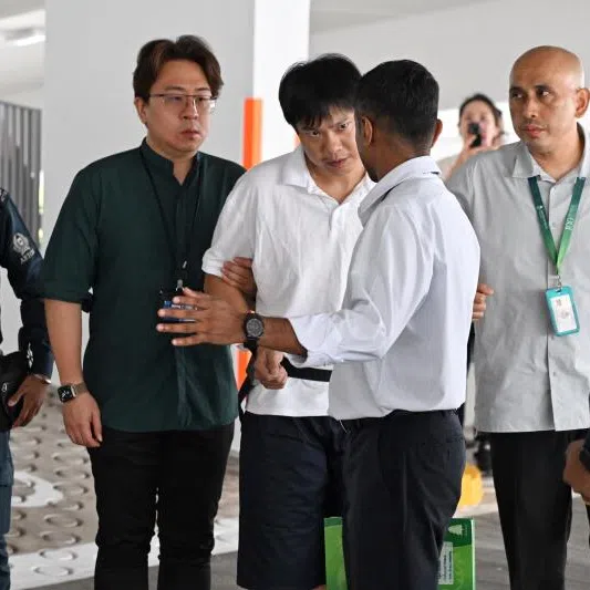 Kong Qi Cong (centre) being escorted by auxiliary police officers and HSA investigation officers to a multi-storey carpark at Block 226D Compassvale Walk on June 30. He is accused of being in possession of Kpods.
