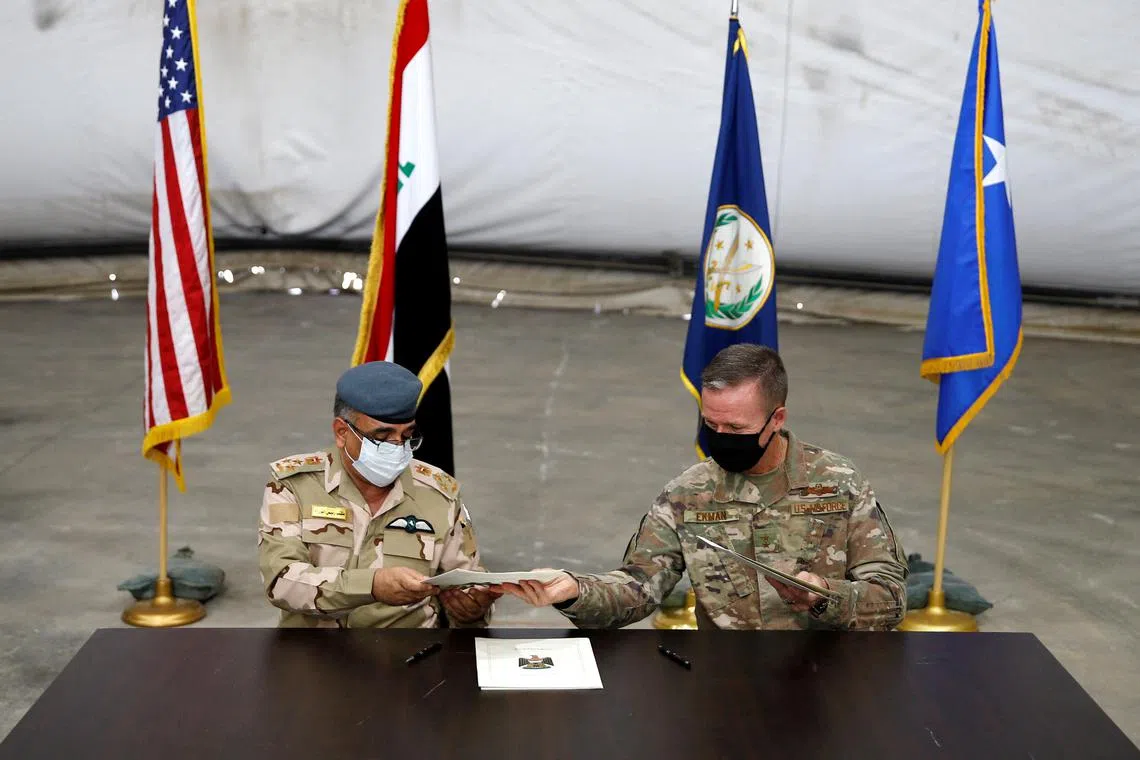 FILE PHOTO: Maj. Gen. Kenneth P. Ekman, Deputy Commander of Combined Joint Task Force-Operation Inherent Resolve, signs documents with Brigadier General Salah Abdullah during a handover ceremony of Taji military base from US-led coalition troops to Iraqi security forces, in the base north of Baghdad, Iraq August 23, 2020. REUTERS/Thaier Al-Sudani/File Photo