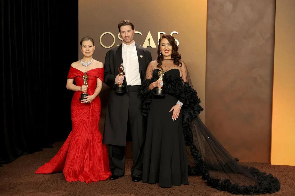 (From left) Maggie Kang, Chris Appelhans, and Michelle L.M. Wong, winners of the Best Animated Feature Film Award for KPop Demon Hunters, pose in the press room during the 98th Oscars at Dolby Theatre on March 15.