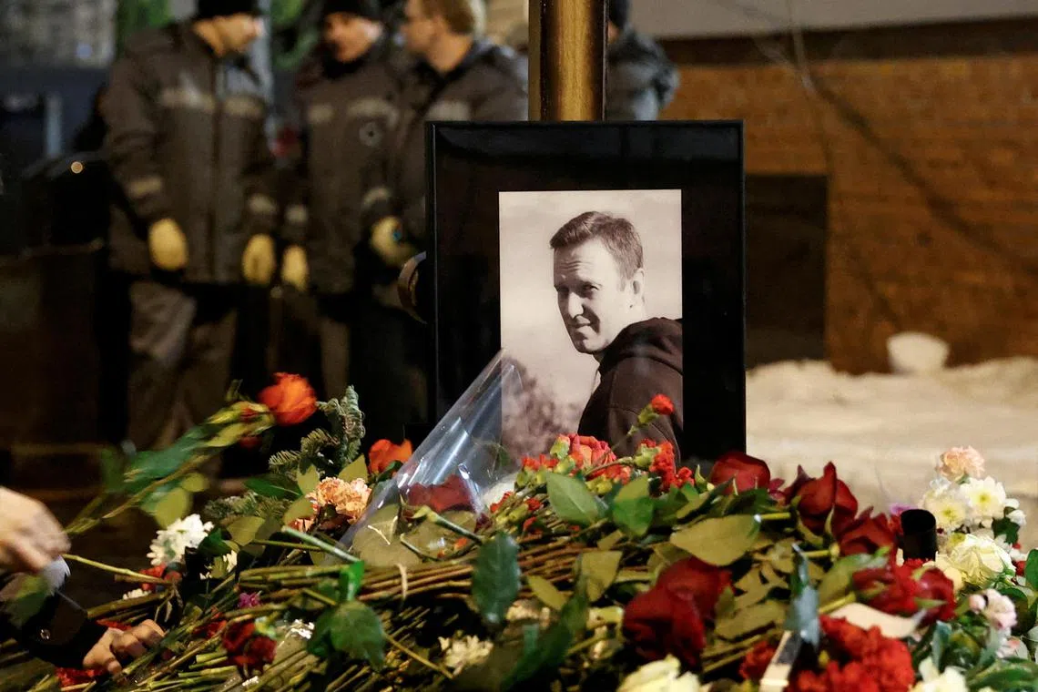 People lay flowers at the grave of Russian opposition politician Alexei Navalny following his funeral at the Borisovskoye cemetery in Moscow on  March 1.