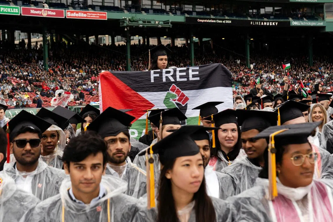 A Northeastern student holds a pro-Palestinian flag during a commencement ceremony at Fenway Park in Boston, Mass. on May 5, 2024. The war in Gaza, combined with tensions over student protests in the past several weeks, had an unmistakable presence at some commencement ceremonies on Sunday. (Sophie Park/The New York Times)
