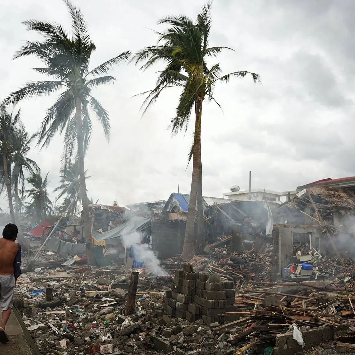 Residents burning wood from their destroyed houses near the seawall at Garchitorena in Camarines Sur province, south of Manila, Philippines on Nov 10, 2025, a day after Super Typhoon Fung-wong made landfall. 