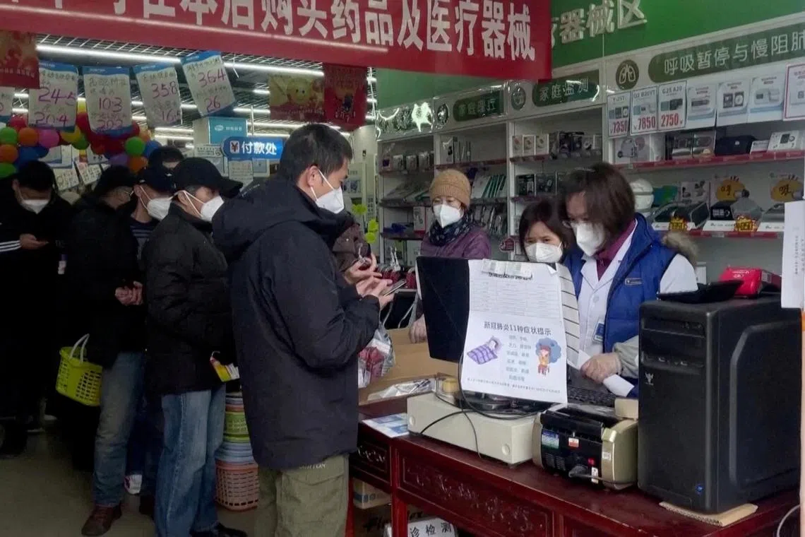 People stand in a queue to purchase medicines at a pharmacy in Beijing, on Dec 14, 2022. 