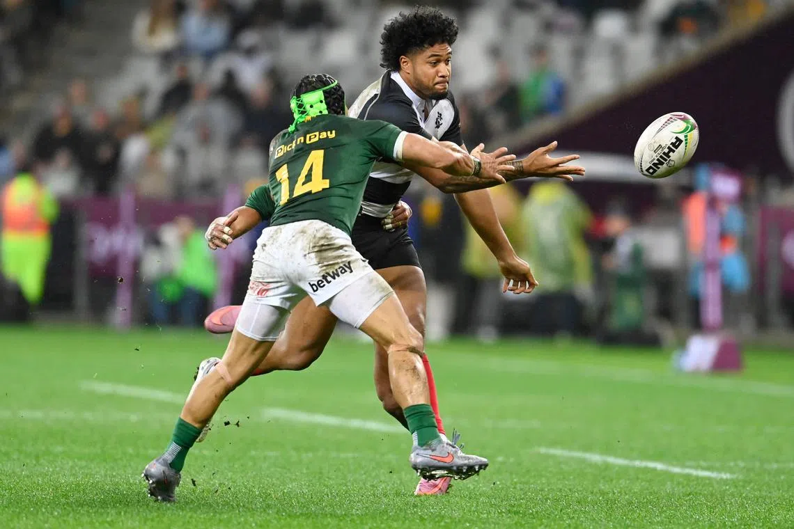 Barbarians' New Zealand outside centre Leicester Fainga'anuku passes the ball to avoid a tackle by South Africa's right-wing Cheslin Kolbe in their International rugby union match at the DHL Stadium in Cape Town on June 28, 2025.