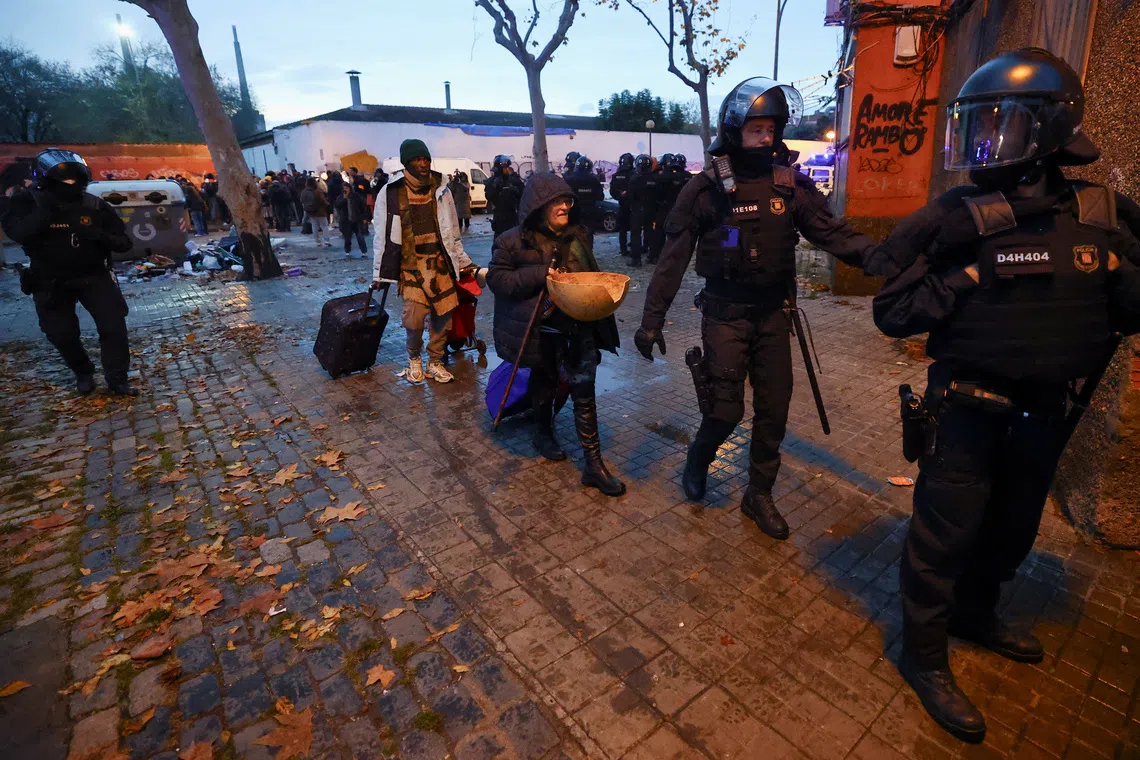 Police officers evict migrants from a former school in Badalona, Spain, December 17, 2025. REUTERS/Albert Gea