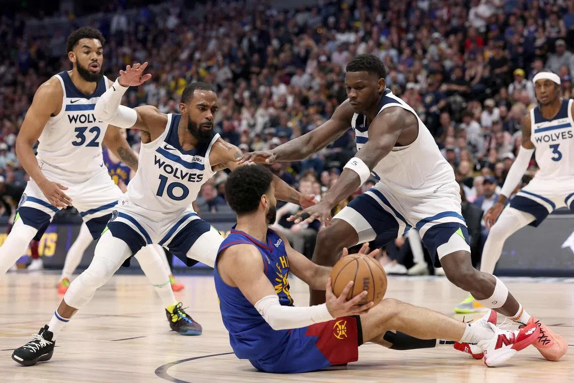 Denver Nuggets' Jamal Murray looking for an outlet while being guarded by Mike Conley (No. 10) and Anthony Edwards of the Minnesota Timberwolves in Game 1 of the Western Conference semi-final series at Ball Arena on May 4.