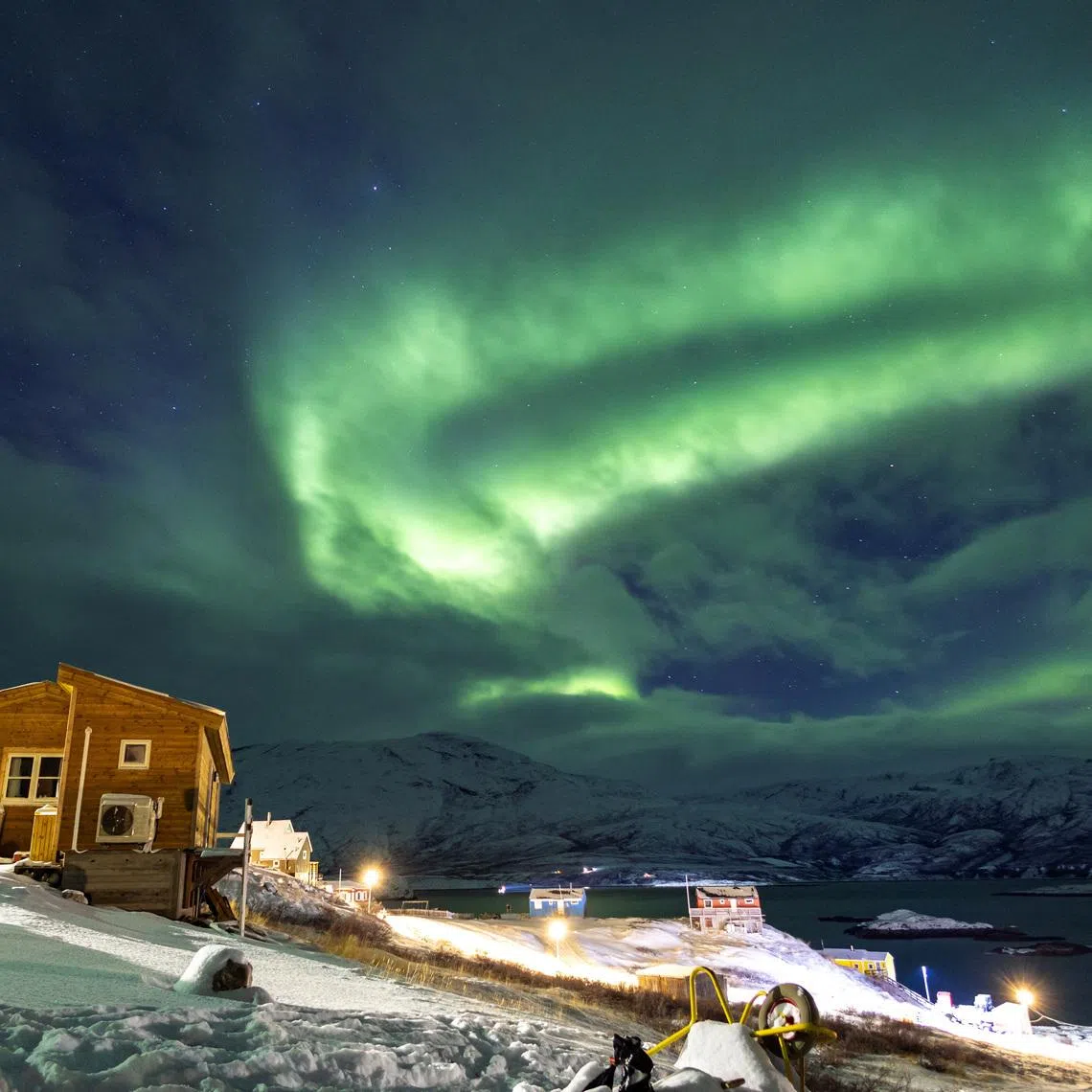 The Aurora Borealis, also known as the \"northern lights\", illuminates the sky over houses in Kapisillit, Greenland. REUTERS/Marko Djurica