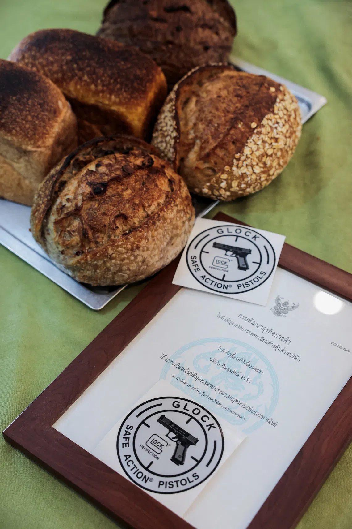 A framed firearms licence and sourdough bread at Suchart and Friends Gun Shop in Bangkok’s historic gun district, where the shop has operated since 1956 and switched to selling sourdough bread because it could no longer import firearms for sale.