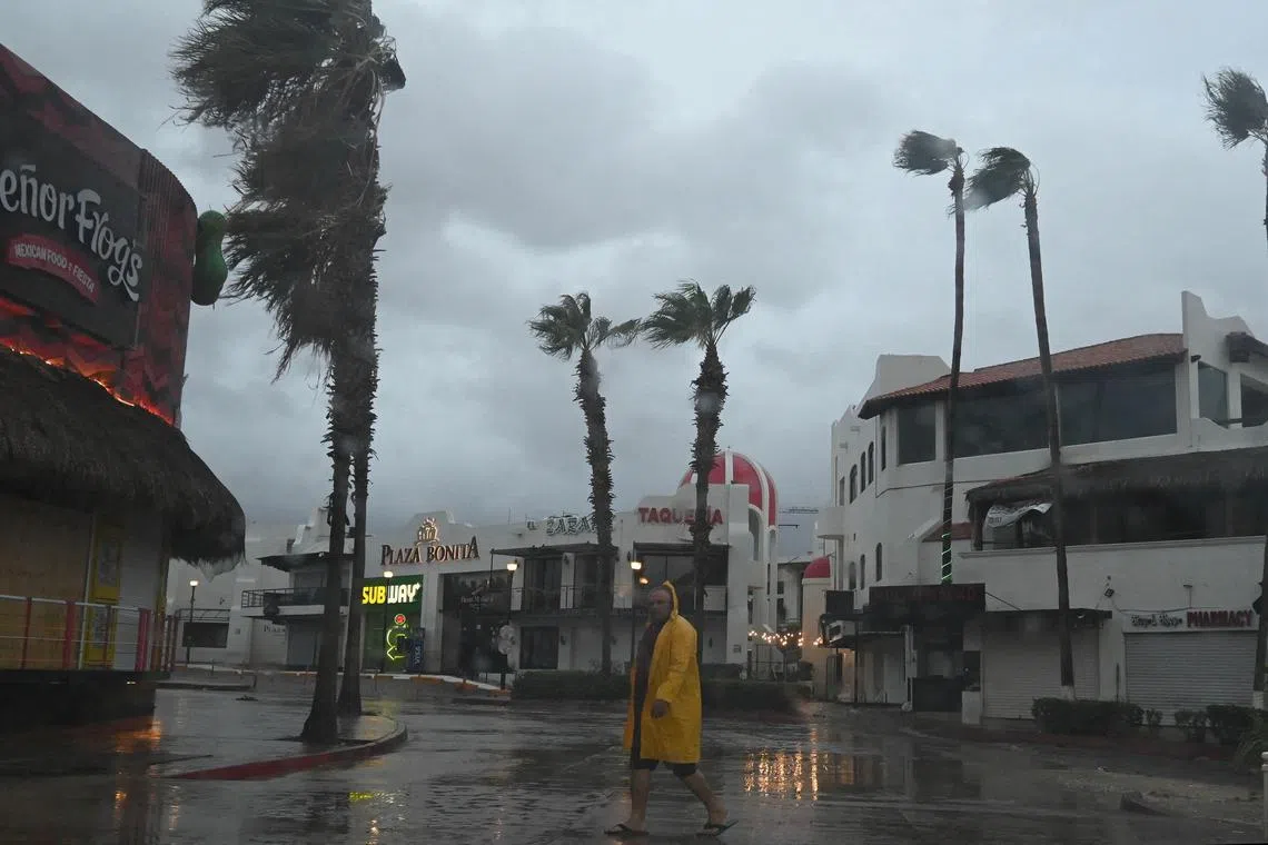 A man walking along a street in Cabo San Lucas as rain and gusts of wind from Hurricane Hilary reach the area on Saturday. 