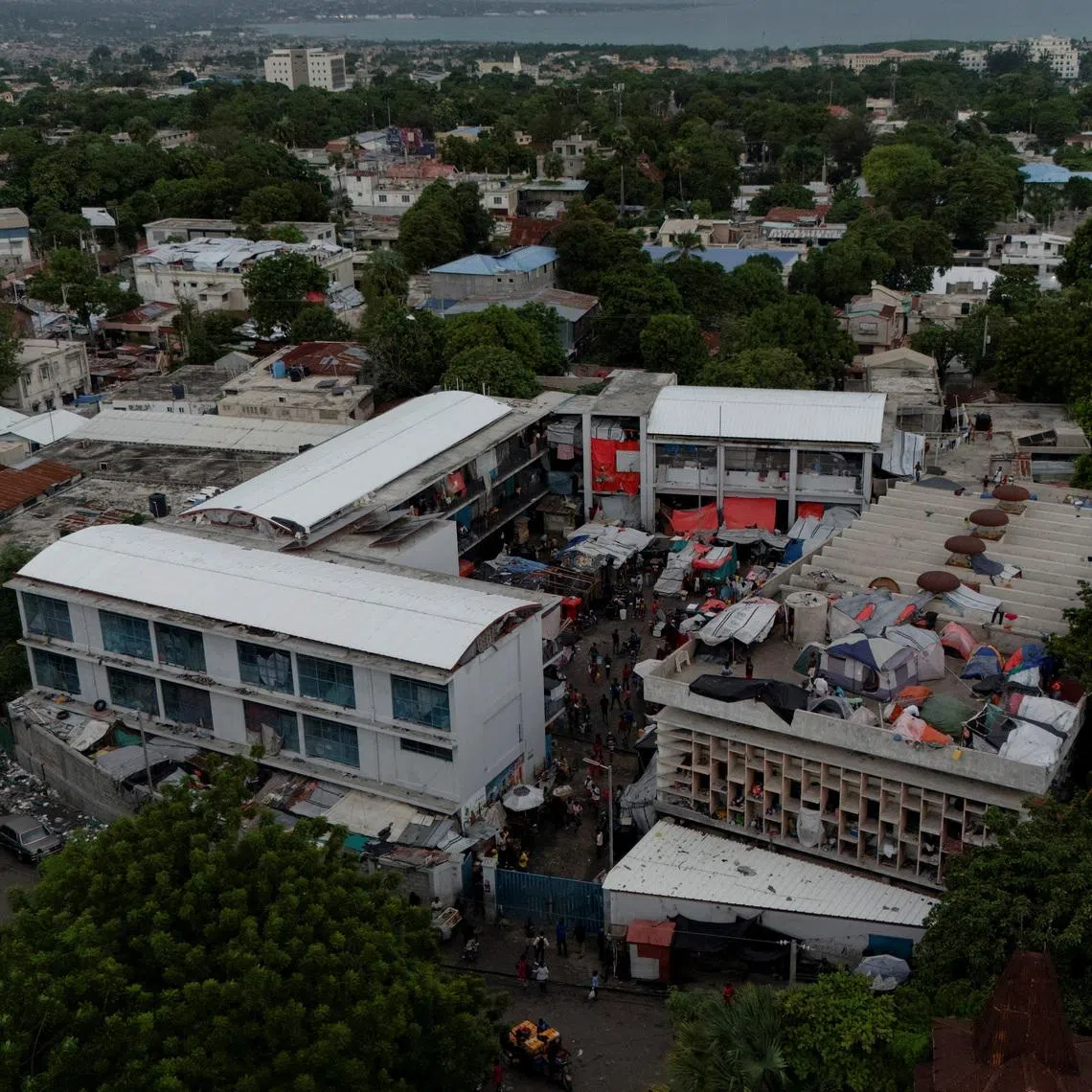 FILE PHOTO: A drone view shows makeshift tents and people camping on the roof at the Lycee Marie-Jeanne, a school turned into a shelter for some of the more than 1.3 million Haitians who have been internally displaced due to gang violence, in Port-au-Prince, Haiti, October 28, 2025. REUTERS/Herbert Villarraga/File Photo
