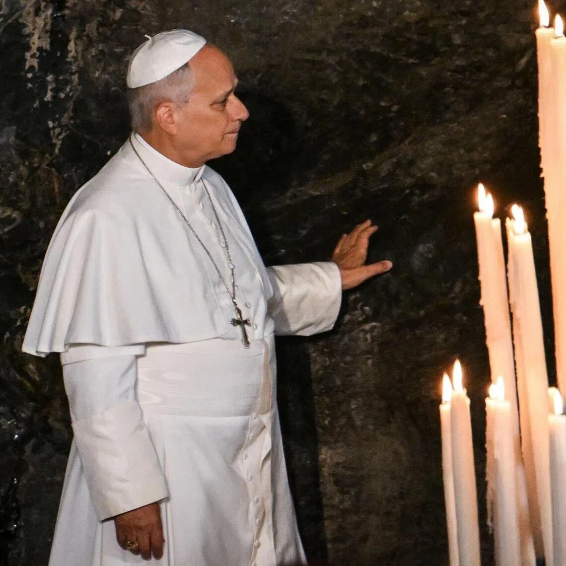 Pope Leo XIV touches the rock at the Grotto of Massabielle, in the Sanctuary of Our Lady of Lourdes, during a prayer with worshippers on Sept 26.