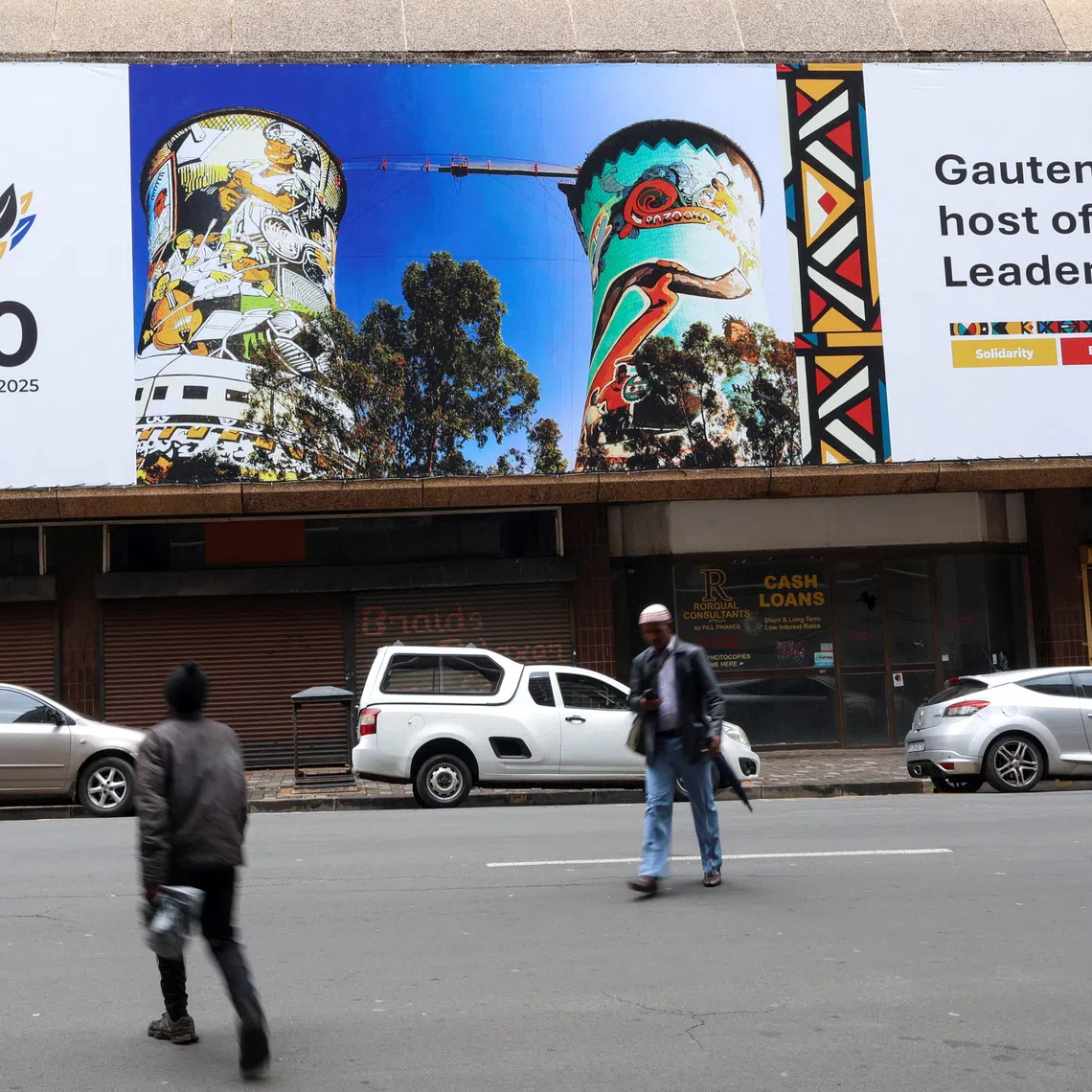 People walk in front a G20 banner, as the country prepares to host the G20 Summit on November 22-23, in Johannesburg, South Africa, November 18, 2025. REUTERS/Siphiwe Sibeko