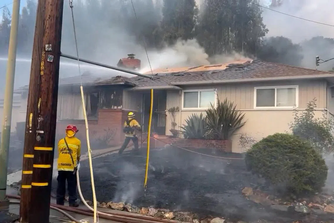 Firefighters work to stop a fire that damaged multiple structures in Oakland, California.