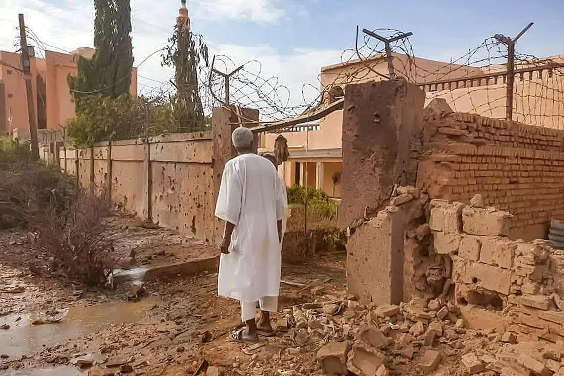 A man walks through rubble by a bullet-riddled fence with barbed-wire, in the aftermath of clashes and bombardment in the Ombada suburb on the western outskirts of Omdurman, the twin city of Sudan's capital, last Monday. 