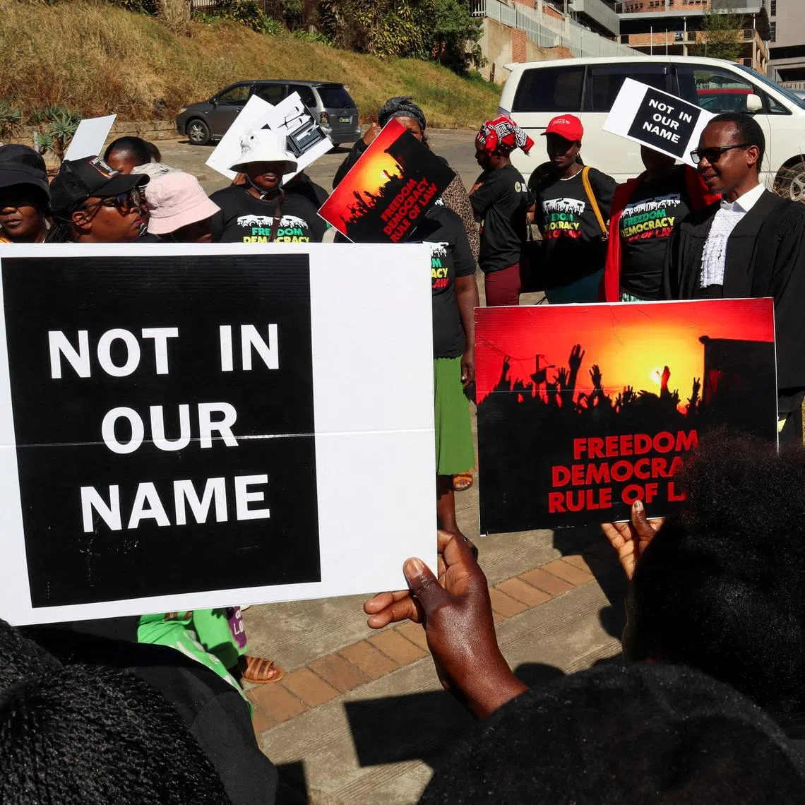 FILE PHOTO: Protesters hold placards as a lawyer addresses them outside the court, after the hearing was postponed, in Mbabane, Eswatini, August 22, 2025. Activists are challenging a secretive agreement with former U.S. President Donald Trump's administration to accept third-country deportees, which they argue is unconstitutional. REUTERS/Zakhele Mabuza/File Photo