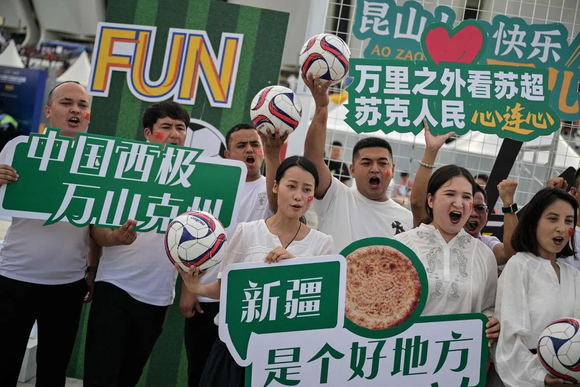 Fans pose for pictures while arriving to watch the amateur league football match between Suzhou and Yangzhou at the Kunshan Olympic Sport Center in Kunshan.