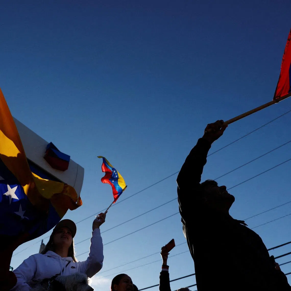 People holding Venezuelan flags react to the news after U.S. President Donald Trump said the U.S. has struck Venezuela and captured its President Nicolas Maduro, in Doral, Miami, Florida, U.S., January 3, 2026. REUTERS/Marco Bello