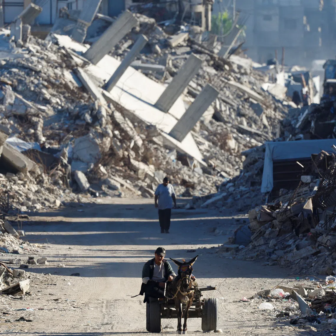 A Palestinian man rides a cart pulled by a donkey amid the rubble of buildings destroyed during the war, in Gaza City, Oct 7.
