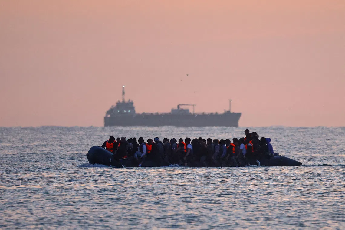 FILE PHOTO: A group of migrants on an inflatable dinghy leave the coast of northern France in an attempt to cross the English Channel to reach Britain as tougher migration controls were announced, from the beach of Petit-Fort-Philippe in Gravelines, near Calais, France, July 17, 2025. REUTERS/Gonzalo Fuentes/File Photo