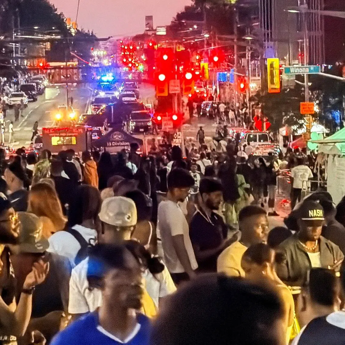 People gather as emergency workers respond at the scene after a deadly shooting, at a salsa-themed street festival in Toronto on July 11.