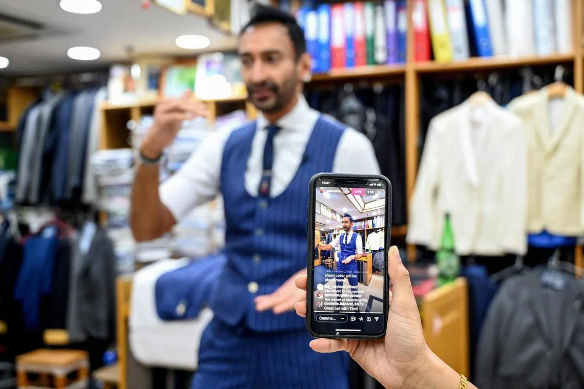 Roshan Melwani of Sam's Tailor is filmed by his team as he talks to a client in the US during a video call at his shop in Hong Kong.