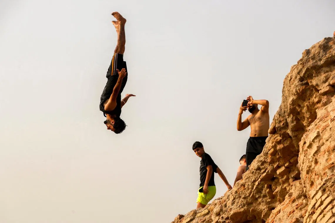 A man diving in the Tigris river to cool off amidst power cuts due to an extreme heatwave in Baghdad on July 15, 2025. 