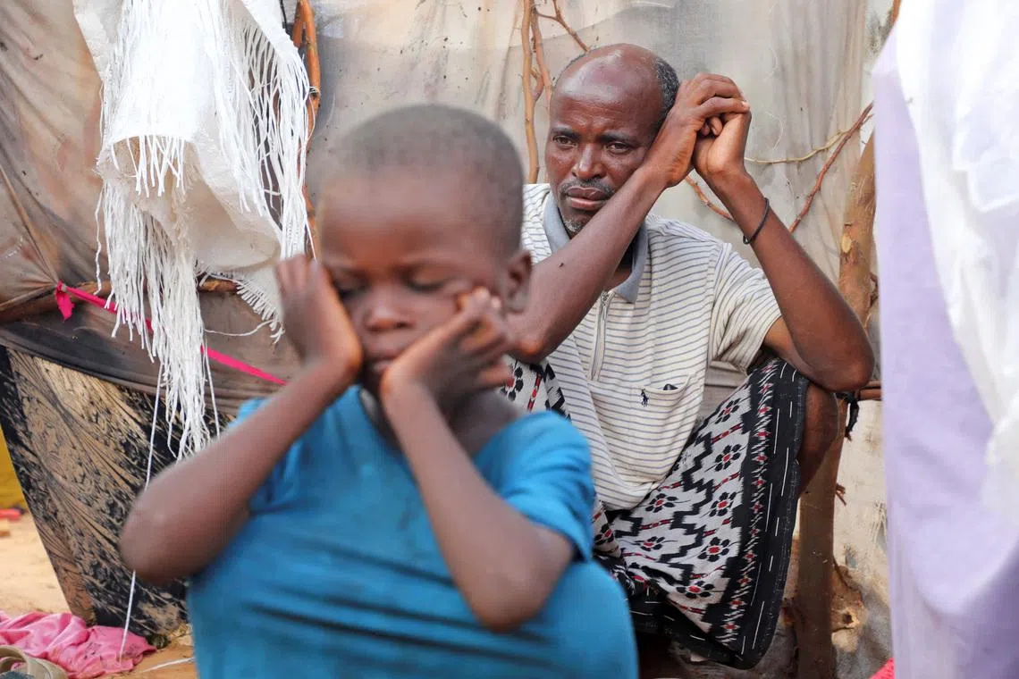 Internally displaced people sit outside their makeshift shelters during a visit by World Food Programme’s Assistant Executive Director for Programme Operations, Matthew Hollingworth (not in the photo), to assess the knock on effects from the escalation in the Middle East, alongside drought and sharp cuts in humanitarian funding that are worsening hunger, in Kahda district of Mogadishu, Somalia May 7, 2026. REUTERS/Feisal Omar