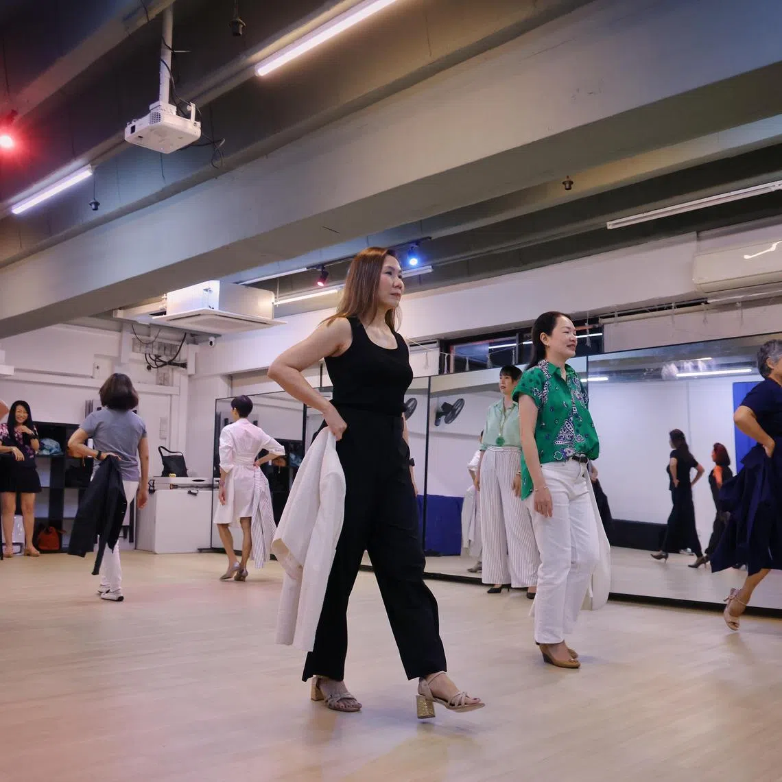 Writer Stephanie Yeo (centre) practises catwalking while taking off her jacket during Platinum Angels Management's modeling atelier course for women over 50. ST PHOTO: JASON QUAH