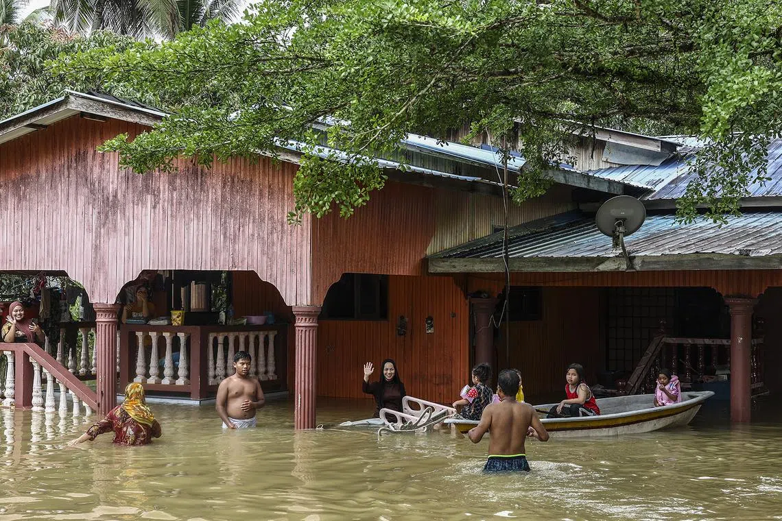 epa11045559 People wade through flood water in Rantau Panjang, in the state of Kelantan, Malaysia, 27 December 2023. More than 28,000 people in four Malaysian states have been evacuated from their homes and are seeking shelter because of worsening flood conditions due to thunderstorms, heavy rains, and strong winds.  EPA-EFE/Stringer