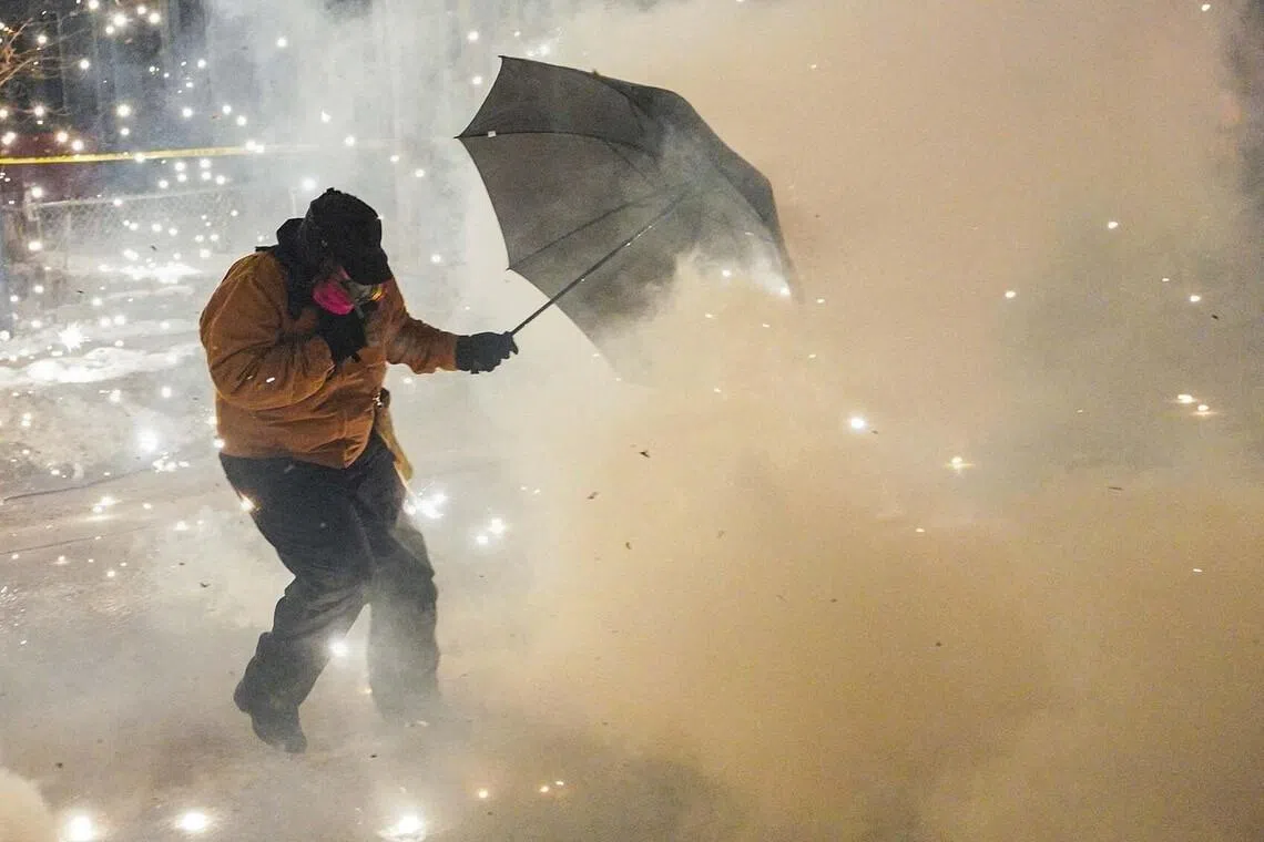 A protesting community member attempts to protect themselves as federal agents fire munitions and pepper balls, as tensions rise after federal law enforcement agents were involved in a shooting incident, a week after a U.S. Immigration and Customs Enforcement (ICE) agent fatally shot Renee Nicole Good, in Minneapolis, Minnesota, U.S., January 14, 2026. REUTERS/Ryan Murphy TPX IMAGES OF THE DAY