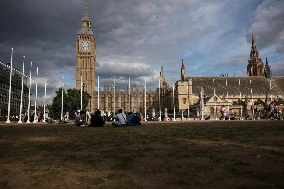 People sitting on dry grass at Parliament Square under an overcast sky in London on Sept 1. More than 80% of England is now in a state of drought.