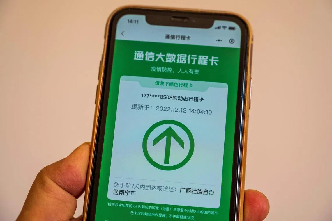 A user holding a mobile phone showing the now-scraped "Itinerary Card" app which is used to track travel to areas with Covid-19.