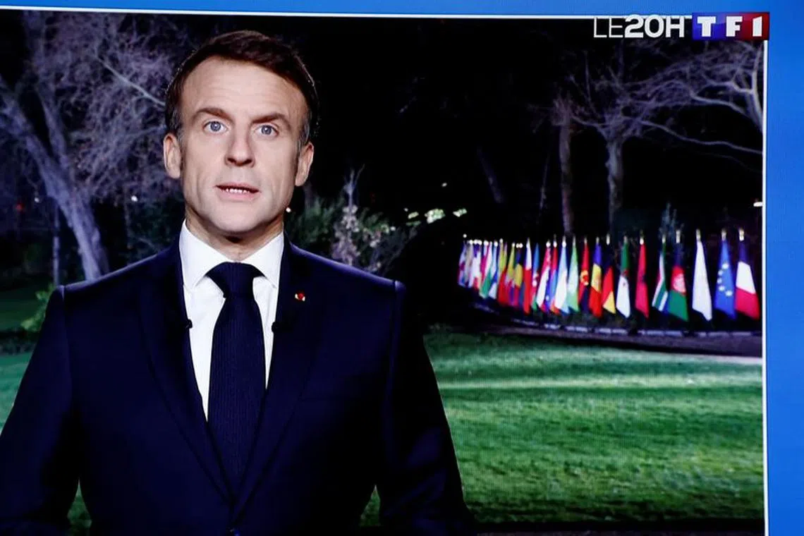 French President Emmanuel Macron is seen on a television screen as he delivers his New Year's speech to the nation at the Elysee Palace in Paris, France, December 31, 2023. REUTERS/Benoit Tessier
