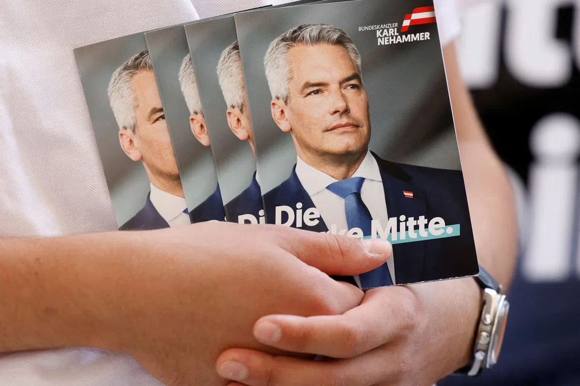 FILE PHOTO: A person holds pictures of Austrian Chancellor and head of Peoples Party Karl Nehammer in Vienna in Vienna, Austria, August 19, 2024. REUTERS/Leonhard Foeger/File Photo