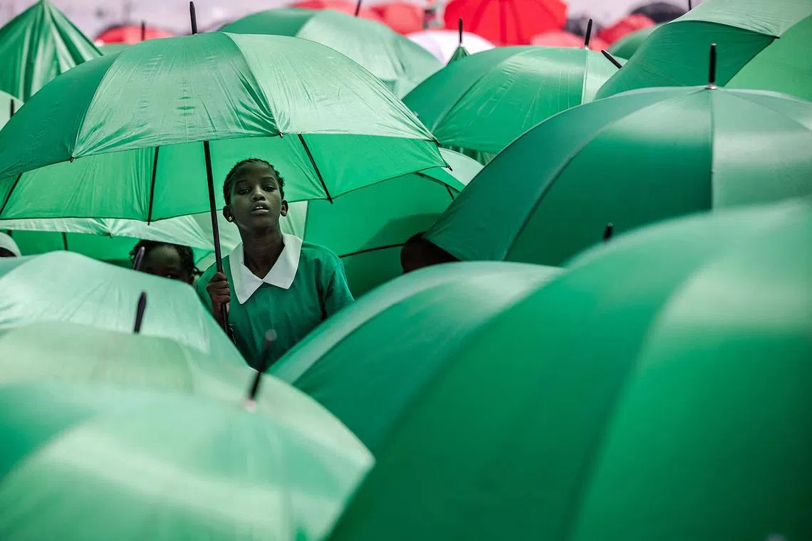 TOPSHOT - Kenyan students hold umbrellas to protect themselves from the sun during the celebrations of Kenya's 60th Independence Day, also known as Jamhuri Day, at the Uhuru Gardens in Nairobi on December 12, 2023. Jamhuri is the Swahili word for 'republic', and the national holiday officially marks the date when Kenya became an independent country from the United Kingdom on December 12, 1963. (Photo by LUIS TATO / AFP)