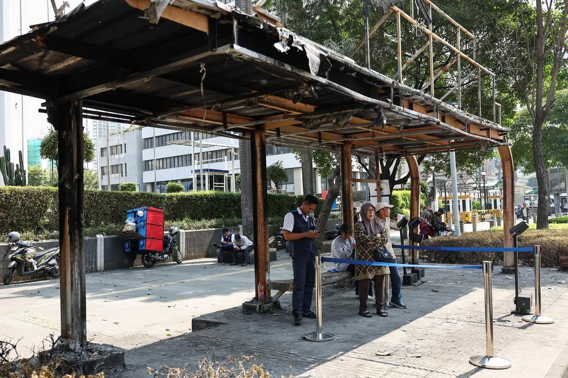 Commuters at a burnt bus stop following a recent protest against police violence, in Jakarta, Indonesia, on Sept 2.