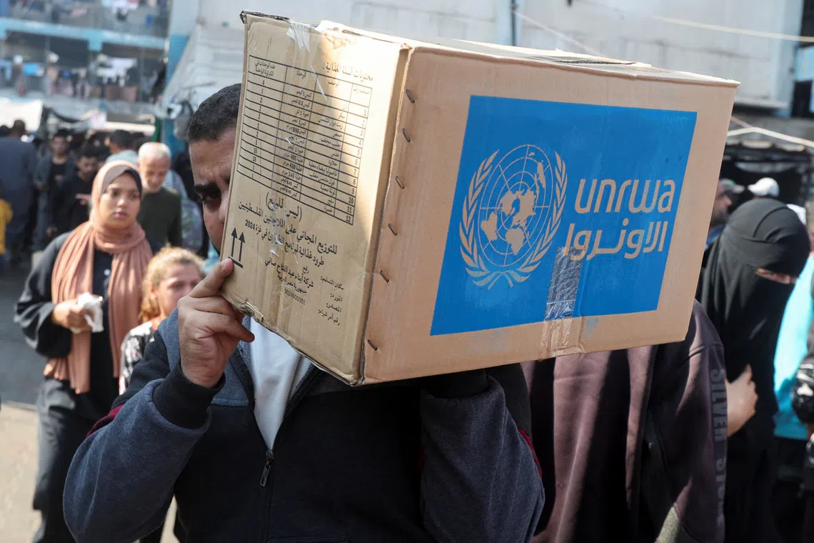 A Palestinian man carries an aid box distributed by the United Nations Relief and Works Agency (UNRWA), amid the Israel-Hamas conflict, in Deir Al-Balah, central Gaza Strip, November 4, 2024. REUTERS/Ramadan Abed