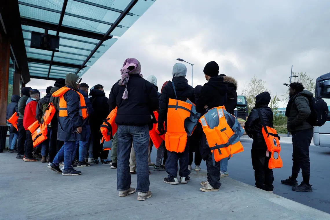 FILE PHOTO: Migrants wait for a bus to return from the beach to their camp, at Calais train station, in Calais, after migrants died in an attempt to cross the English Channel, in France, April 23, 2024. REUTERS/Abdul Saboor/File Photo